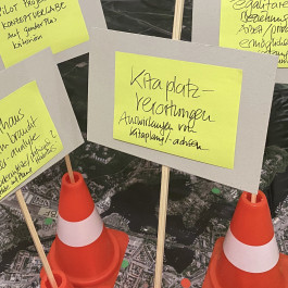 Visuelle Darstellung der Ergebnisse eines Workshops im Projekt „EINE Stadt für ALLE“ - Genderanalyse des Potsdamer Wohnungswesens 2020. Zu sehen ist ein Ausschnitt eines Luftbildes der Stadt Potsdam, auf dem Verkehrsleitkegel stehen, auf denen Moderationskarten angebracht sind. Lesbare Ergebnisse: Notwendigkeit einer Gender-Analyse zur Repräsentation im Stadthaus Potsdam, Pilotprojekt Konzeptvergabe mit Gender-Plus-Kriterien, Auswirkungen der Kitaplanung auf die Kitaplatzverortung, Rolle der Milieuschutzsatzung für die Förderung egalitärer räumlicher Beziehungen und für die Balance zwischen Arbeit und Privatleben 
